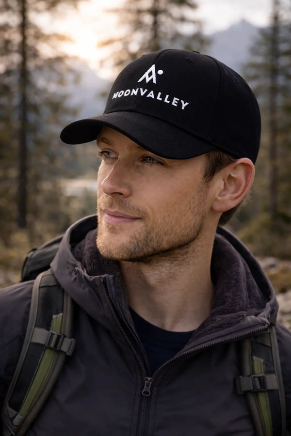 Man wearing a black cap with 'Moonvalley' logo in a forest setting
