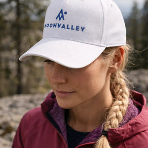 Person wearing a white cap with 'Moonvalley' logo outdoors