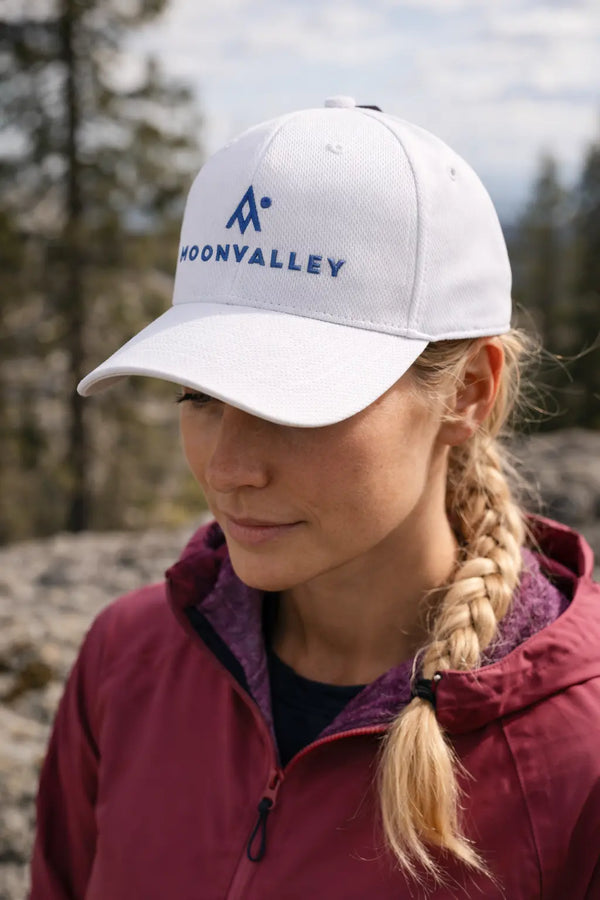 Person wearing a white cap with 'Moonvalley' logo outdoors