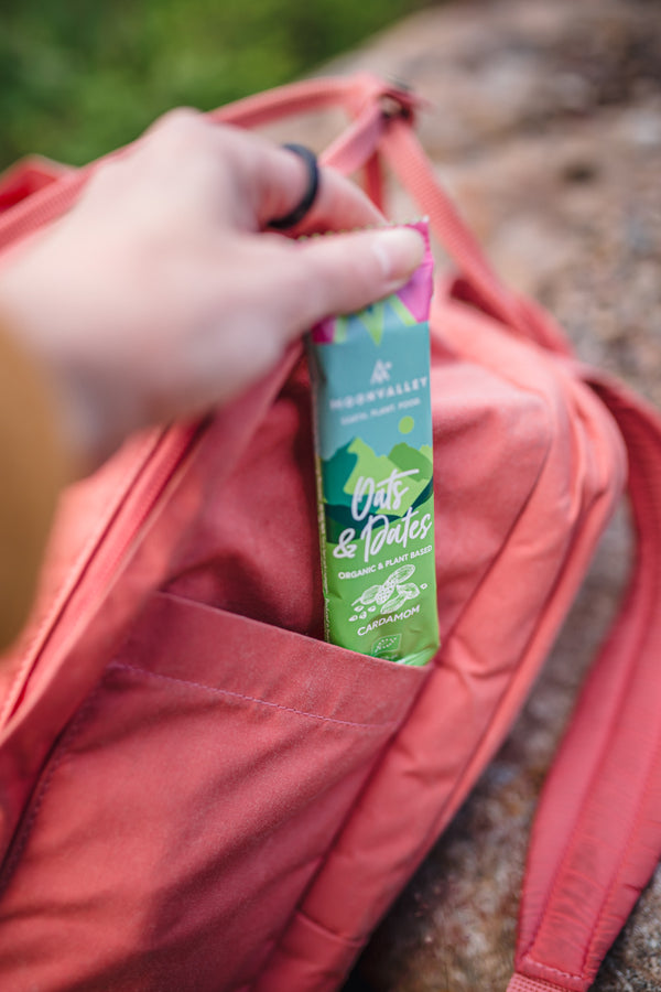 Hand putting an energy bar into a backpack pocket.