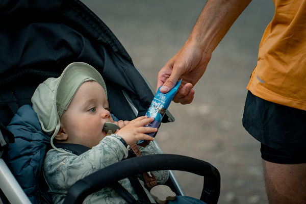 A parent giving a Moonvalley energy bar to a child in a stroller.