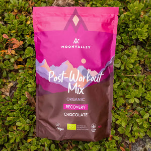 Moonvalley organic chocolate recovery drink powder, photographed in a natural outdoor setting.