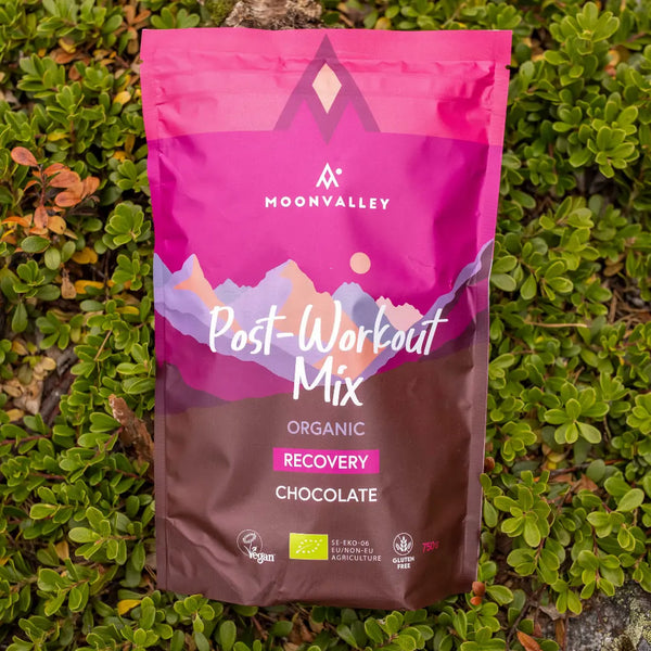 Moonvalley organic chocolate recovery drink powder, photographed in a natural outdoor setting.