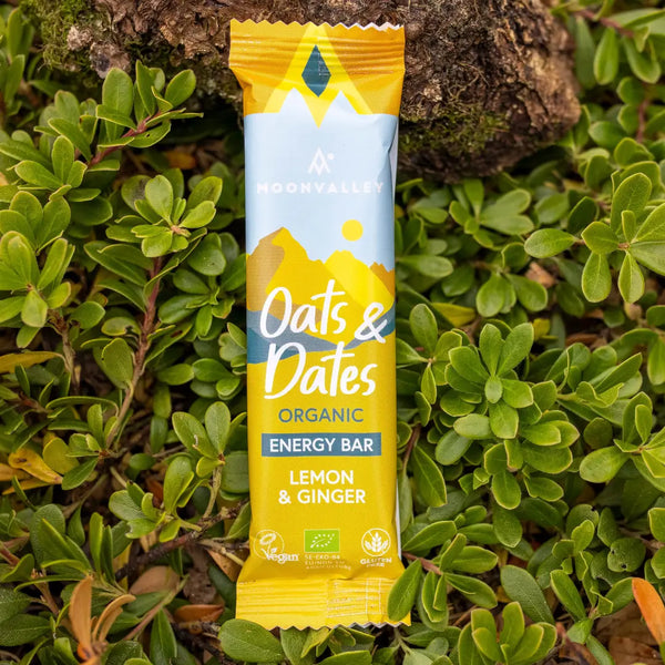 Moonvalley organic Lemon & Ginger energy bar, photographed in a natural outdoor setting.