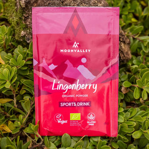 Moonvalley organic Lingonberry sports drink powder, photographed in a natural outdoor setting.