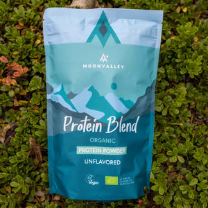 Moonvalley organic unflavoured protein powder in a resealable pouch, photographed in a natural outdoor setting.