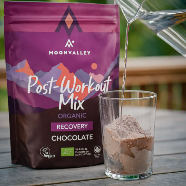 Pouring water into a glass with chocolate Post-Workout powder.