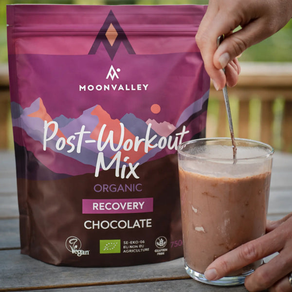 Hand stirring a glass of chocolate Post-Workout drink.
