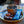 A cup of coffee and a Moonvalley chocolate protein bar on a wooden tray.