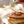 Stack of protein-rich pancakes with syrup and pecans being poured over them on a white plate.