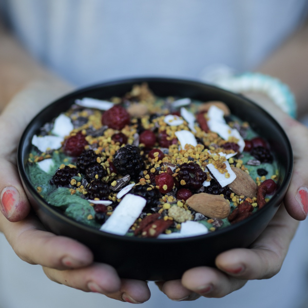 A healthy pourage bowl topped with berries and nuts, using Moonvalley protein powder.
