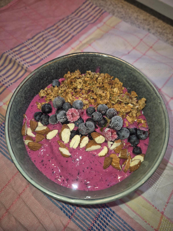 A healthy smoothie bowl topped with berries and nuts, using Moonvalley protein powder.