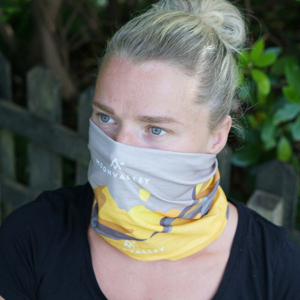 Woman wearing a yellow and grey Moonvalley Mountain Tube over her nose and mouth.
